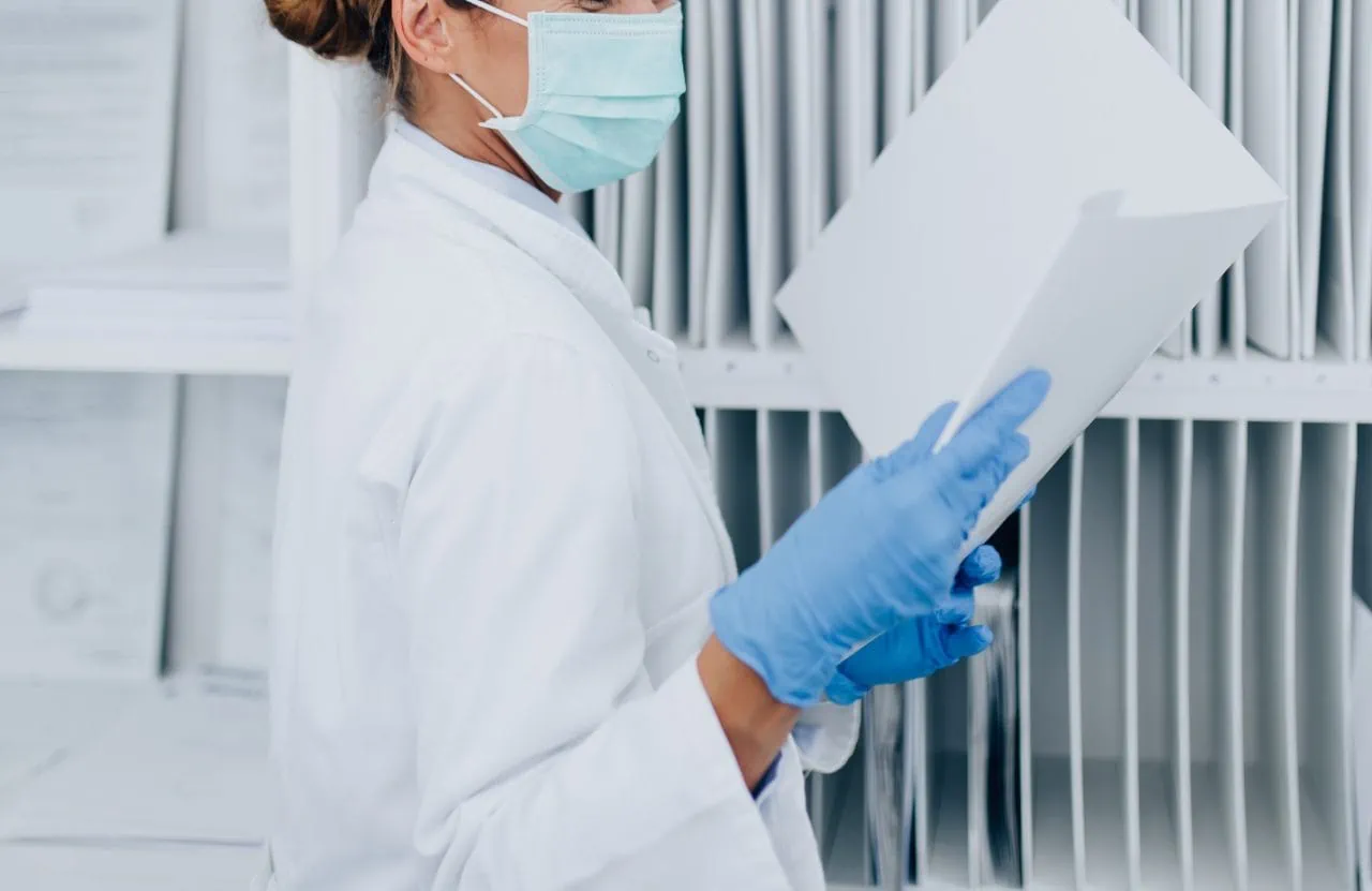 young female practitioner nurse with face protective mask working clinic reception desk