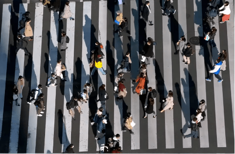 An overhead view of a crowd of people crossing the street at a crosswalk